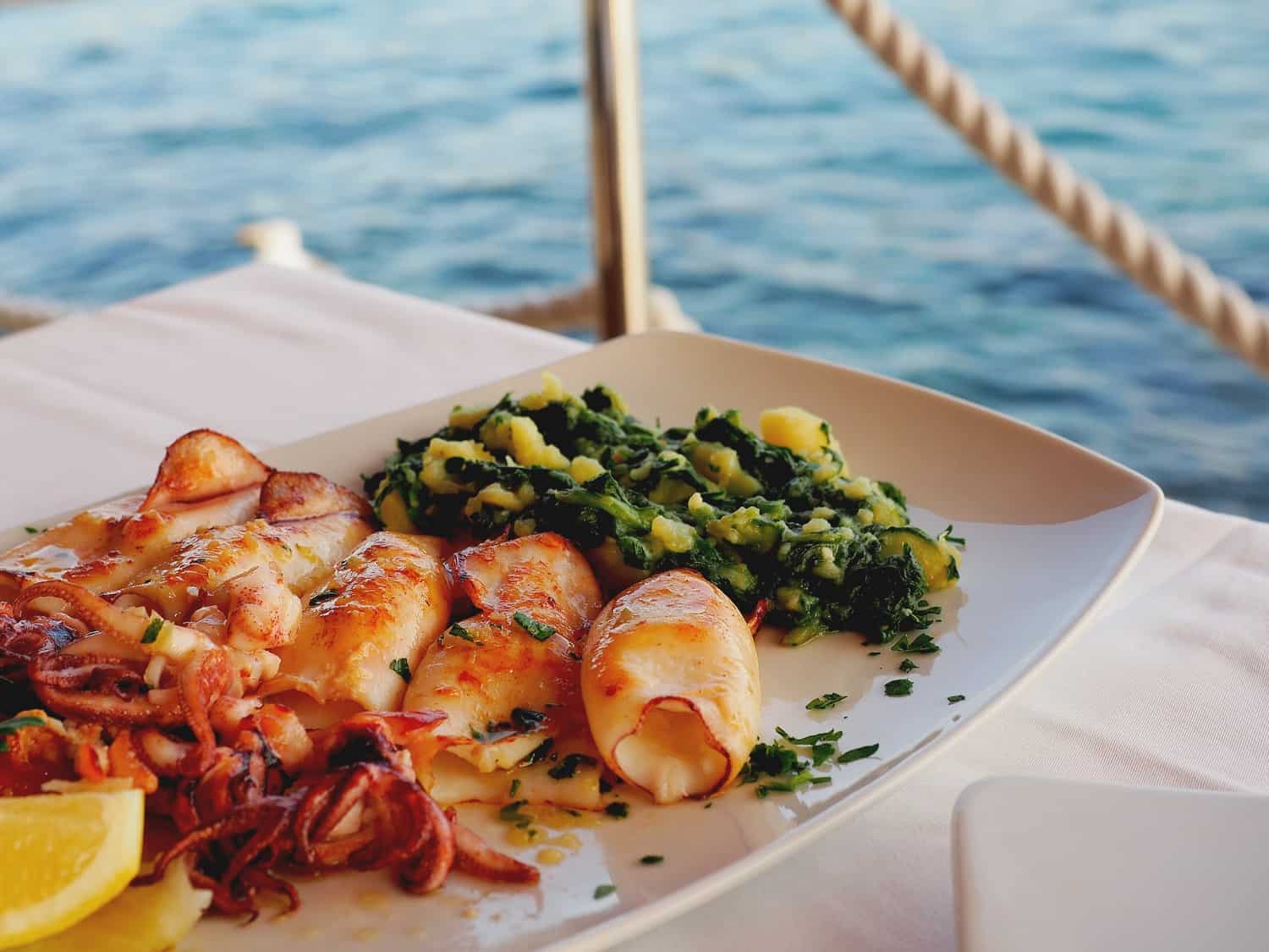 Plate of seafood on a table with a white tablecloth, beside the ocean in Croatia