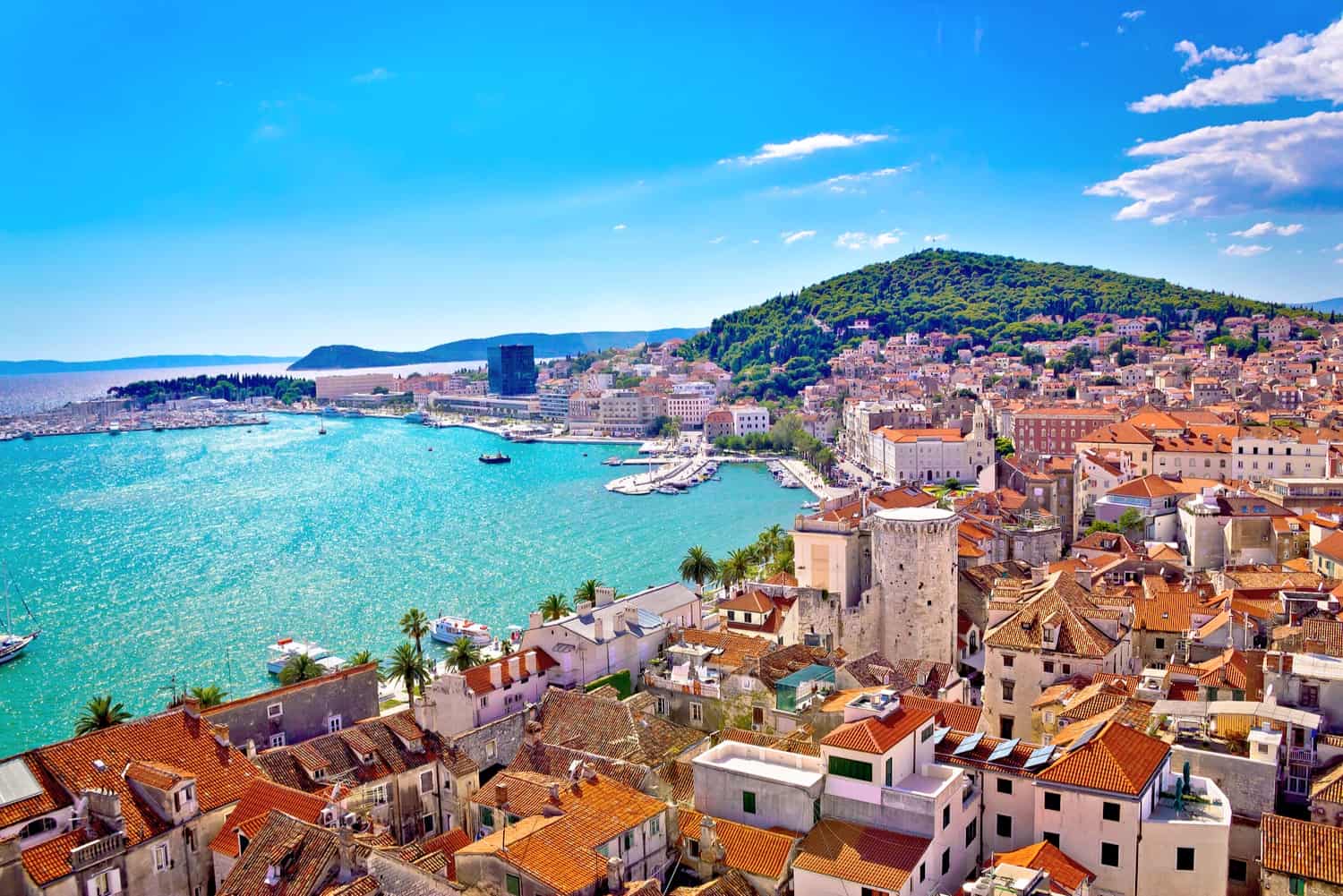 Waterfront in Split, Croatia, with many red-roofed houses and other buildings clustered closely around a small harbour.