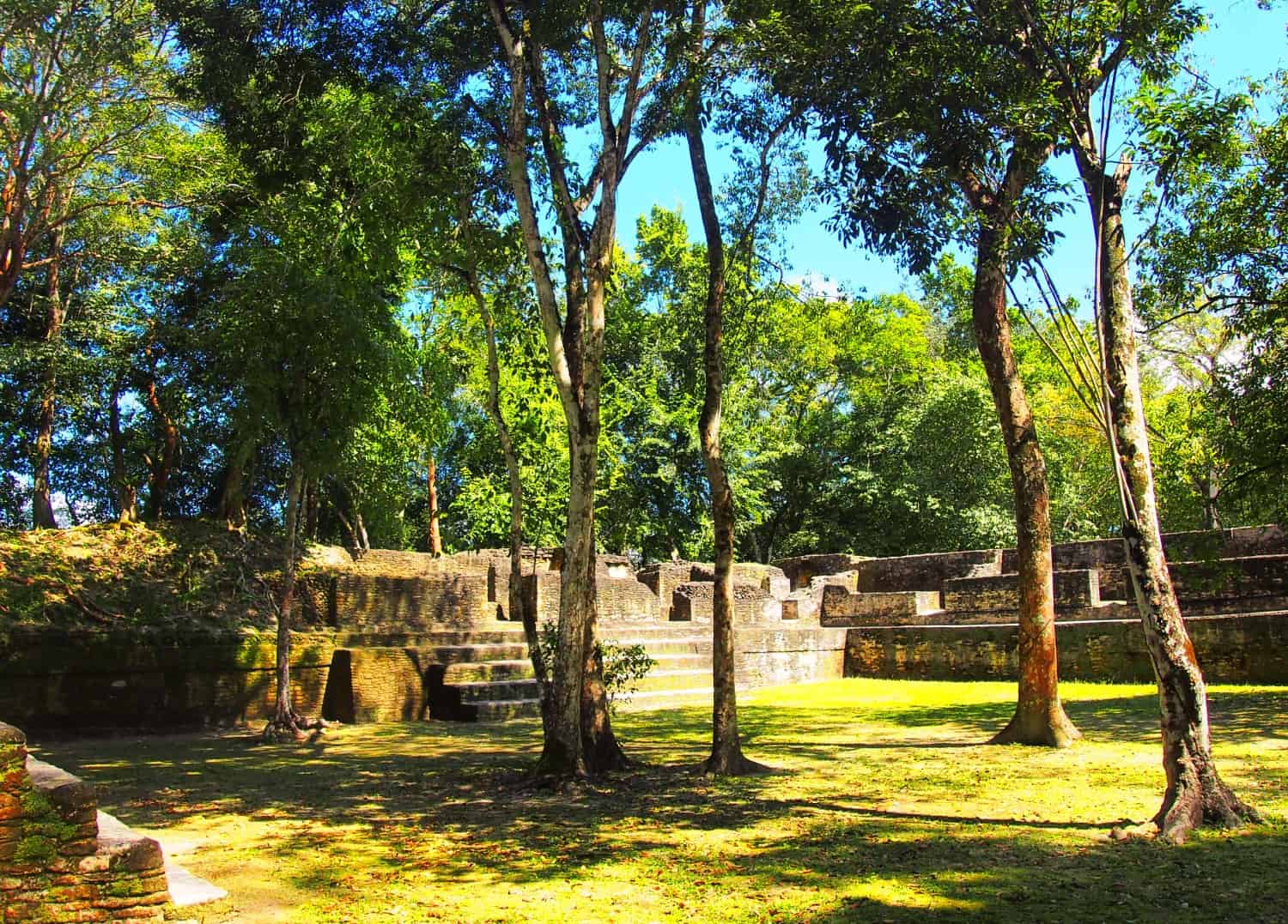 Mayan ruins around an open courtyard with a few trees in the middle, at Cahal Pech, Belize.