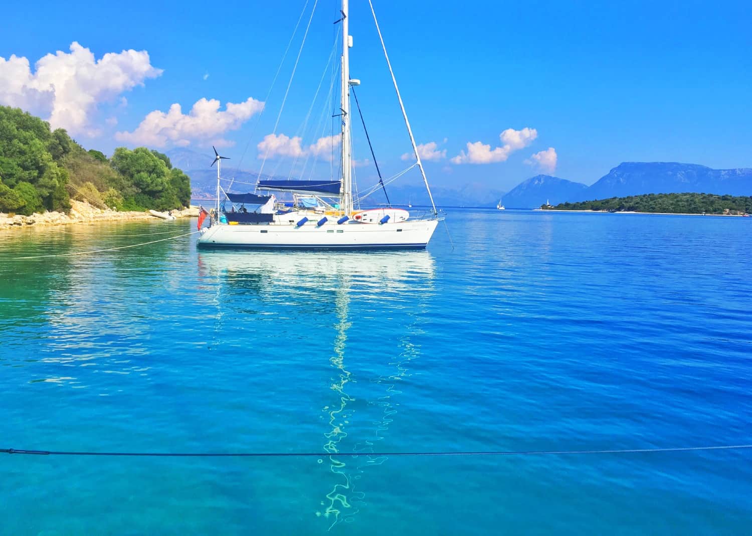 A secluded bay in Greece with a yacht floating on crystal-clear water