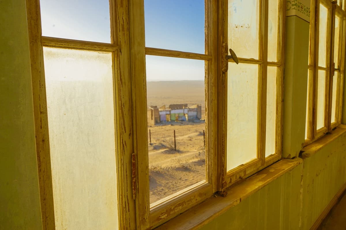 View of the desert through a window at Kolmanskop
