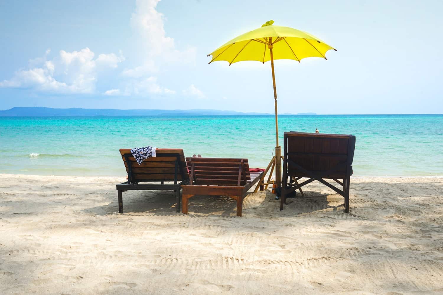 Deckchairs on Thai beach with yellow umbrella