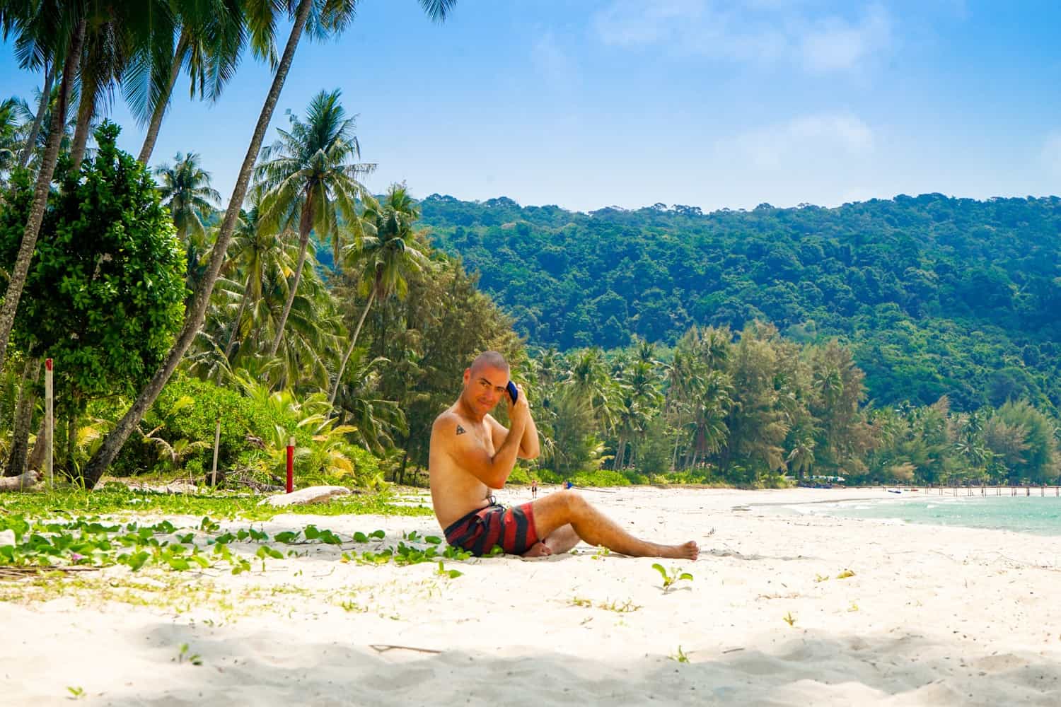 Man shaving his head on the beach