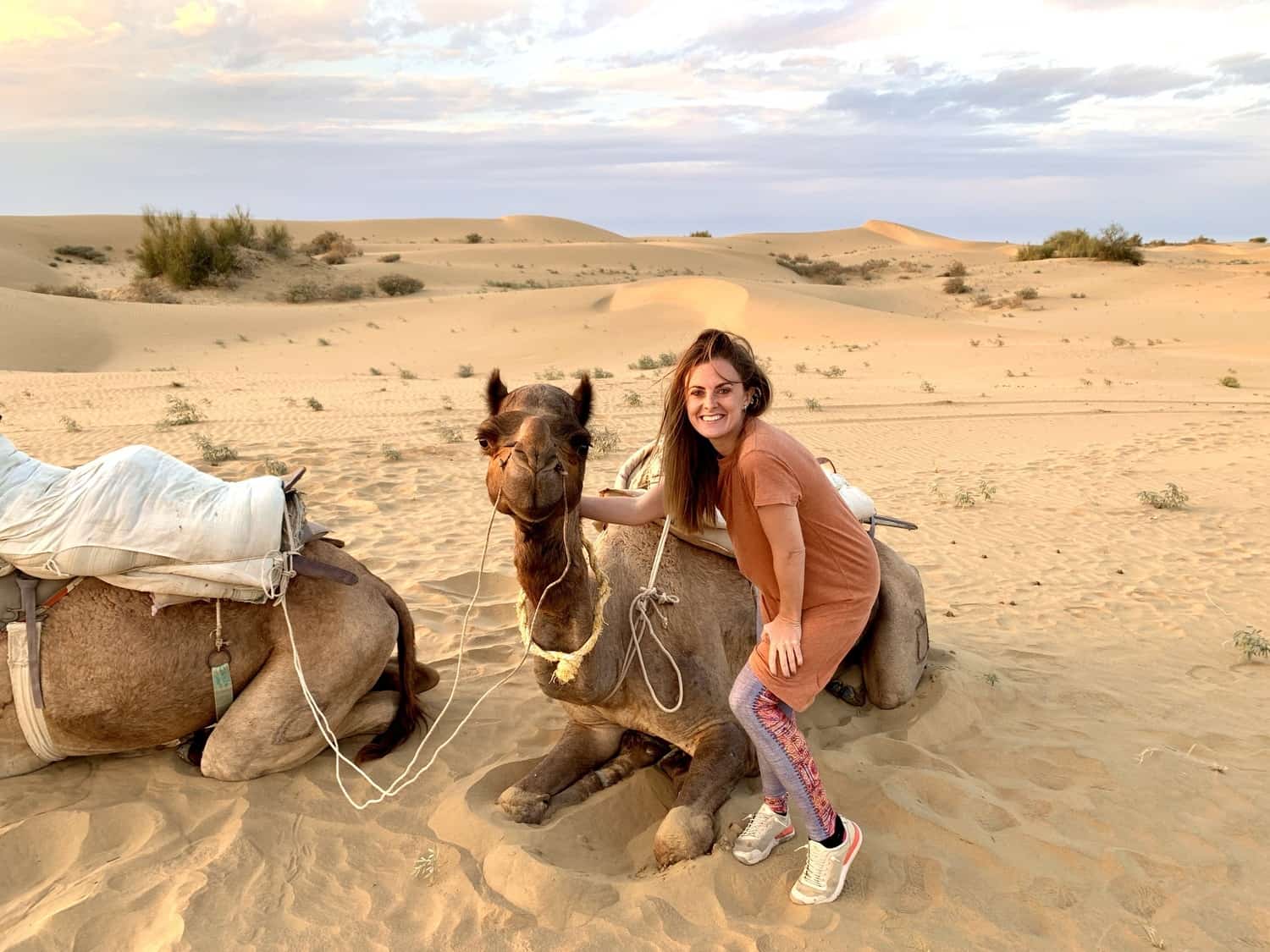 Girl posing beside a smiling camel in the desert