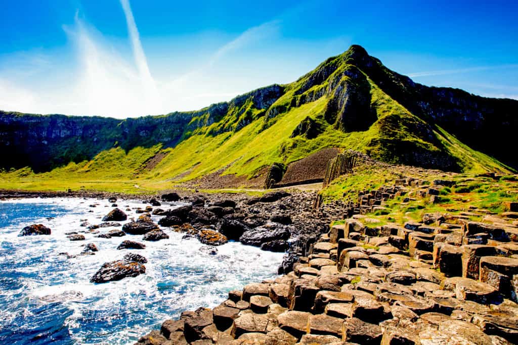 Stepped rocks leading down to a rocky bay, with large hills rising up behind.