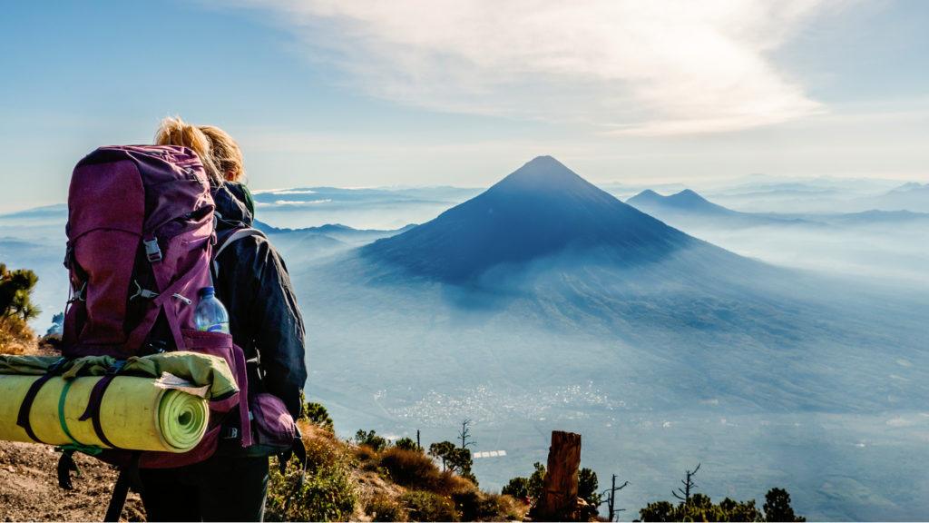 girl wearing a backpack and looking over the volcanoes of guatemala