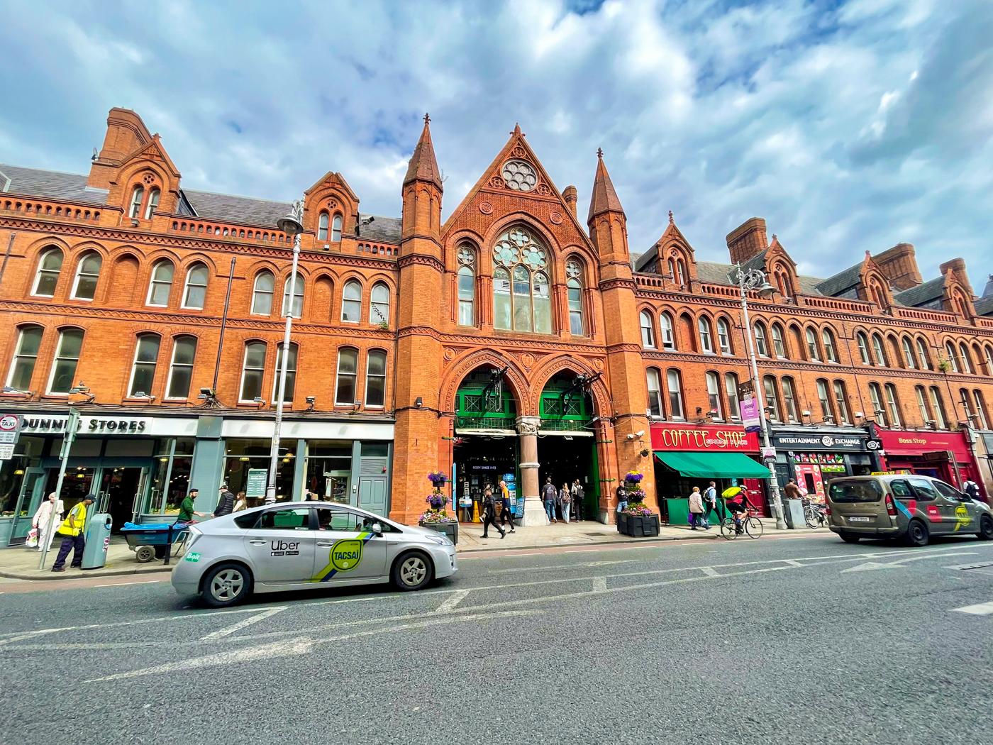 The rustic, brick design of George's Street Arcade looks imposing against the cloudy skies. In the foreground, several taxis drive along the otherwise-empty street.